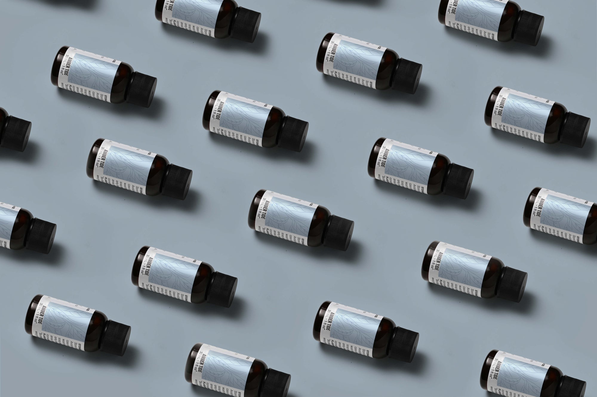 Pattern of Amber Tide fragrance oil bottles on a light dusty blue background