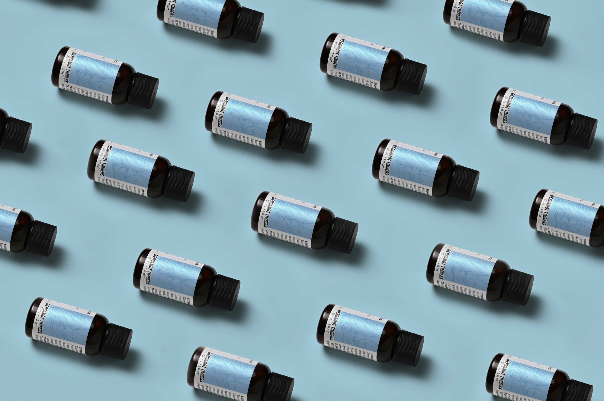 Pattern of Bergamot Timbers fragrance oil bottles on a light blue background