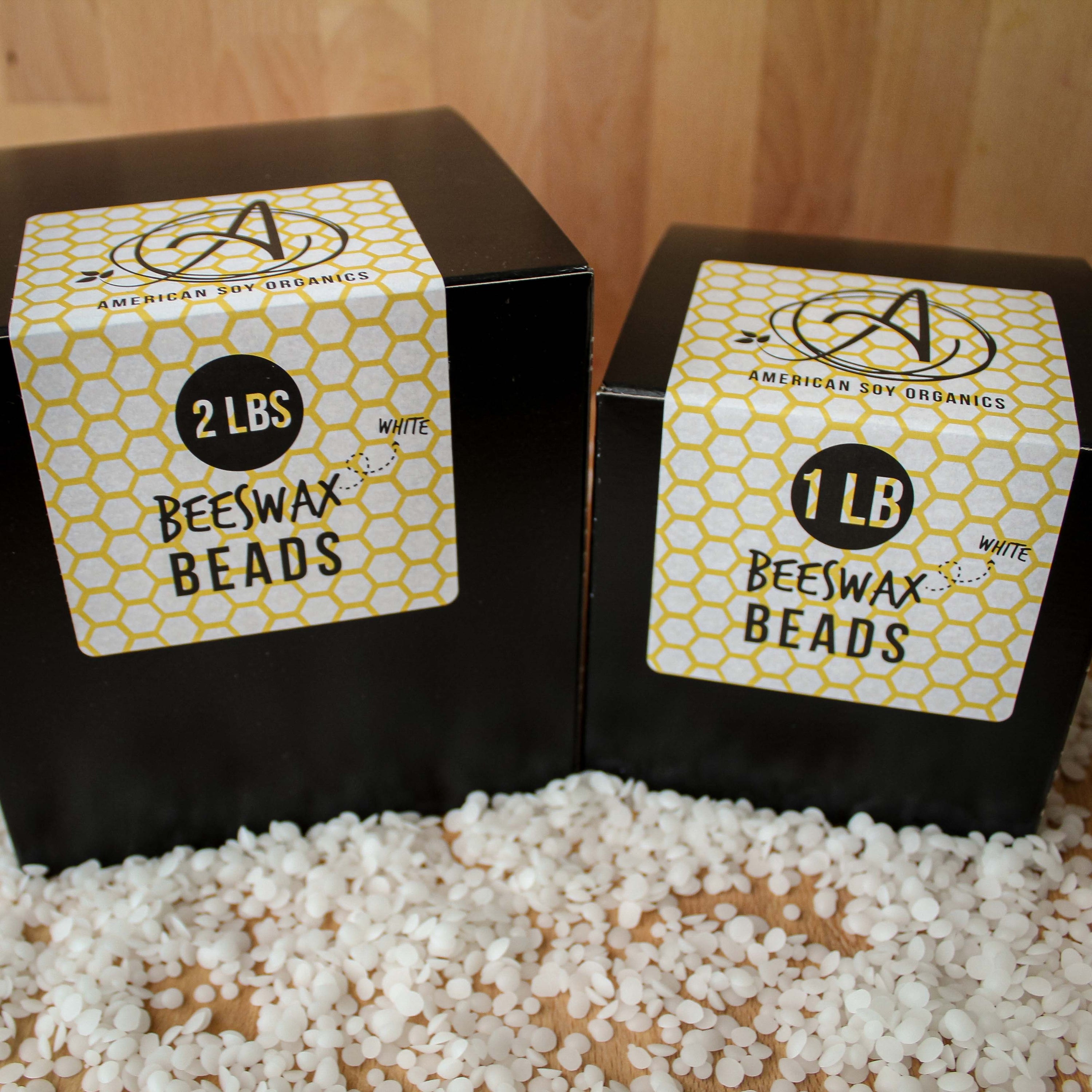 Two boxes of American Soy Organics White Beeswax Beads with labels on a wooden surface.