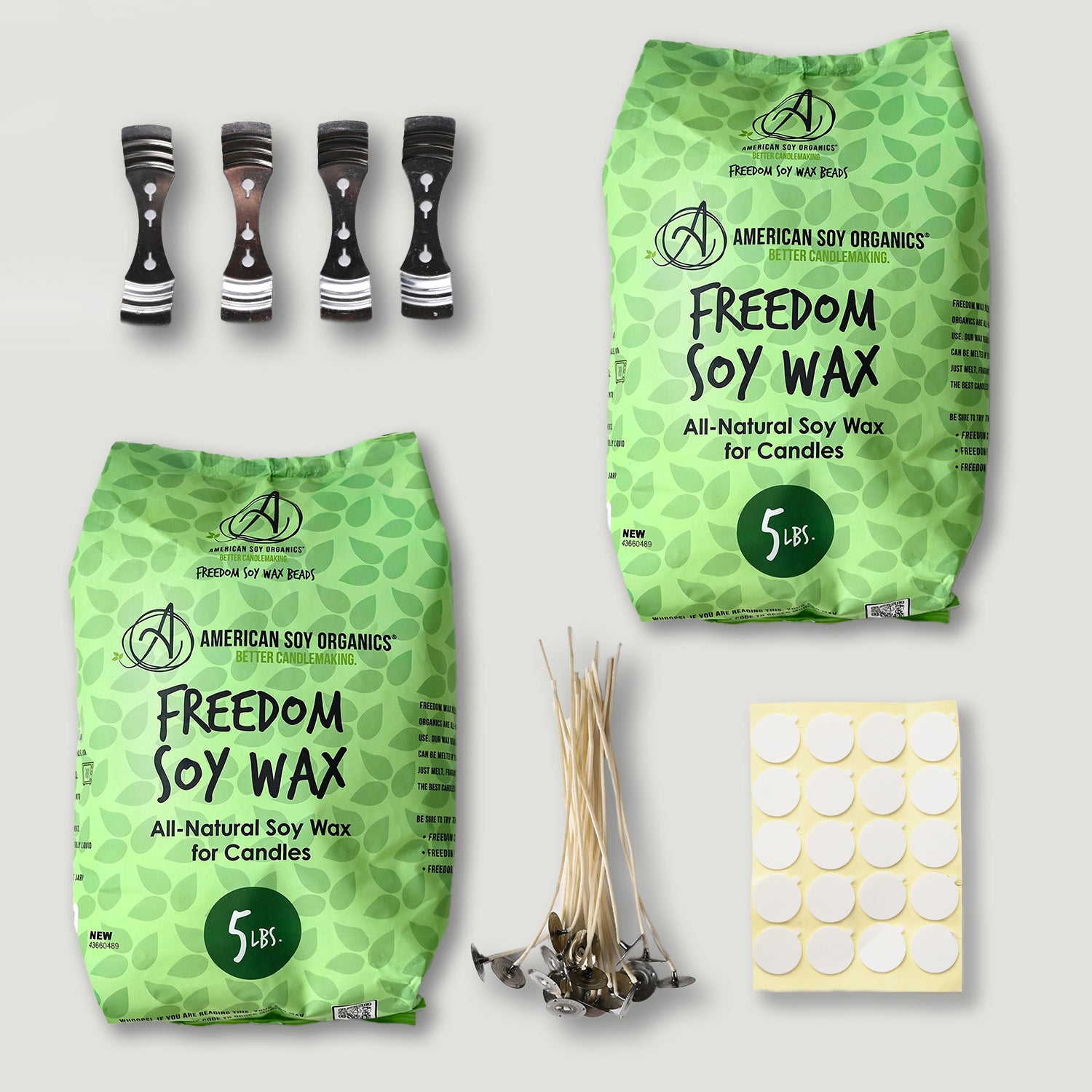 Two packages of American Soy Organics Freedom Soy Wax, candle wicks, and a sheet of stickers on a light gray background.