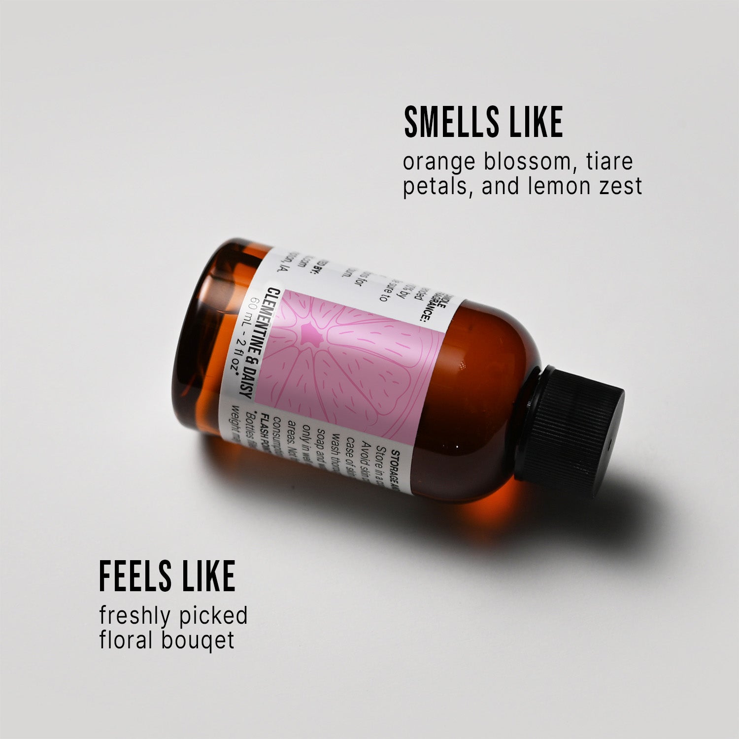 Bottle of Clementine & Daisy fragrance oil with a label on a white background, describing its scent.