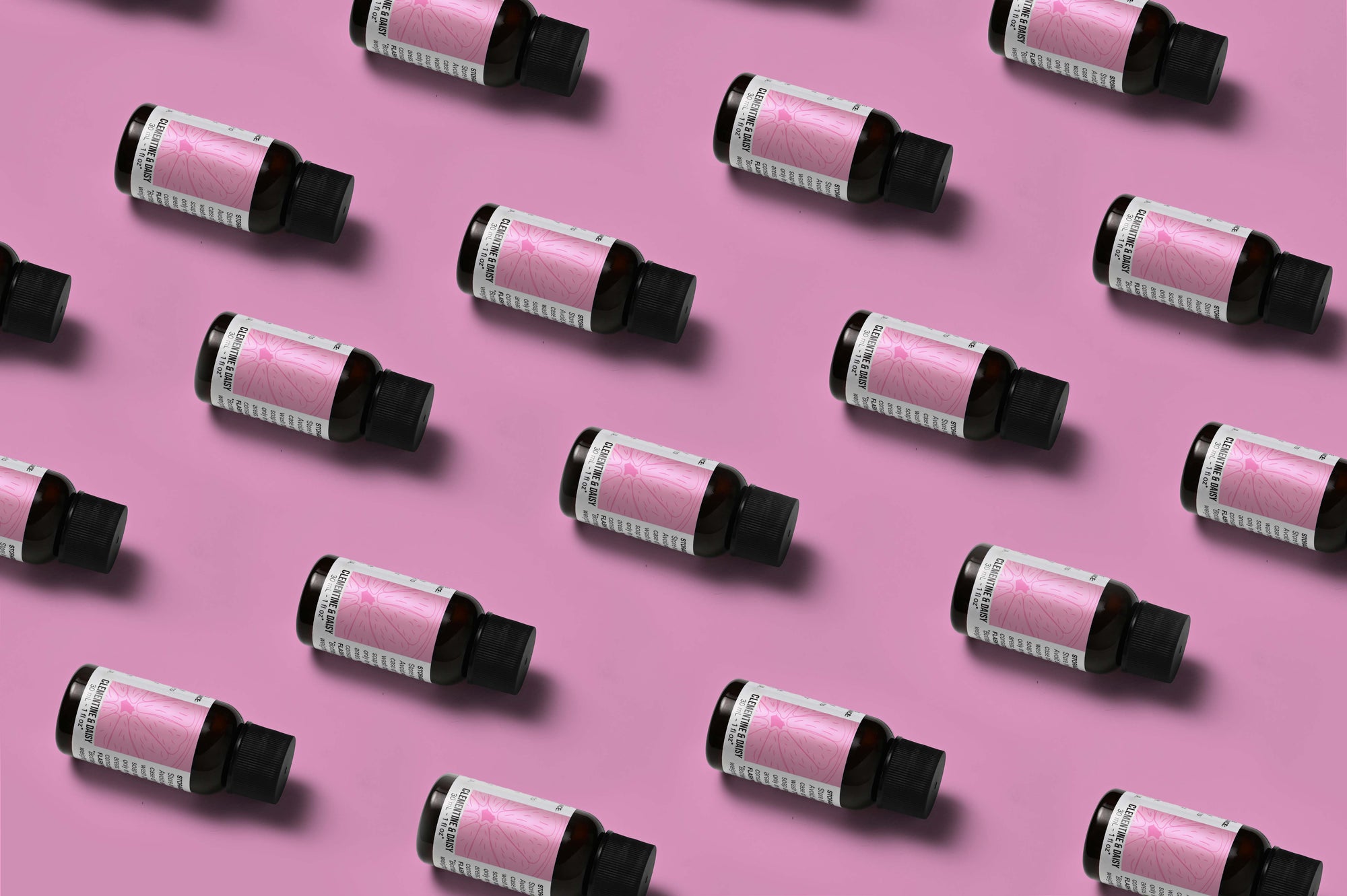 Pattern of Clementine & Daisy fragrance oil bottles on a pink background