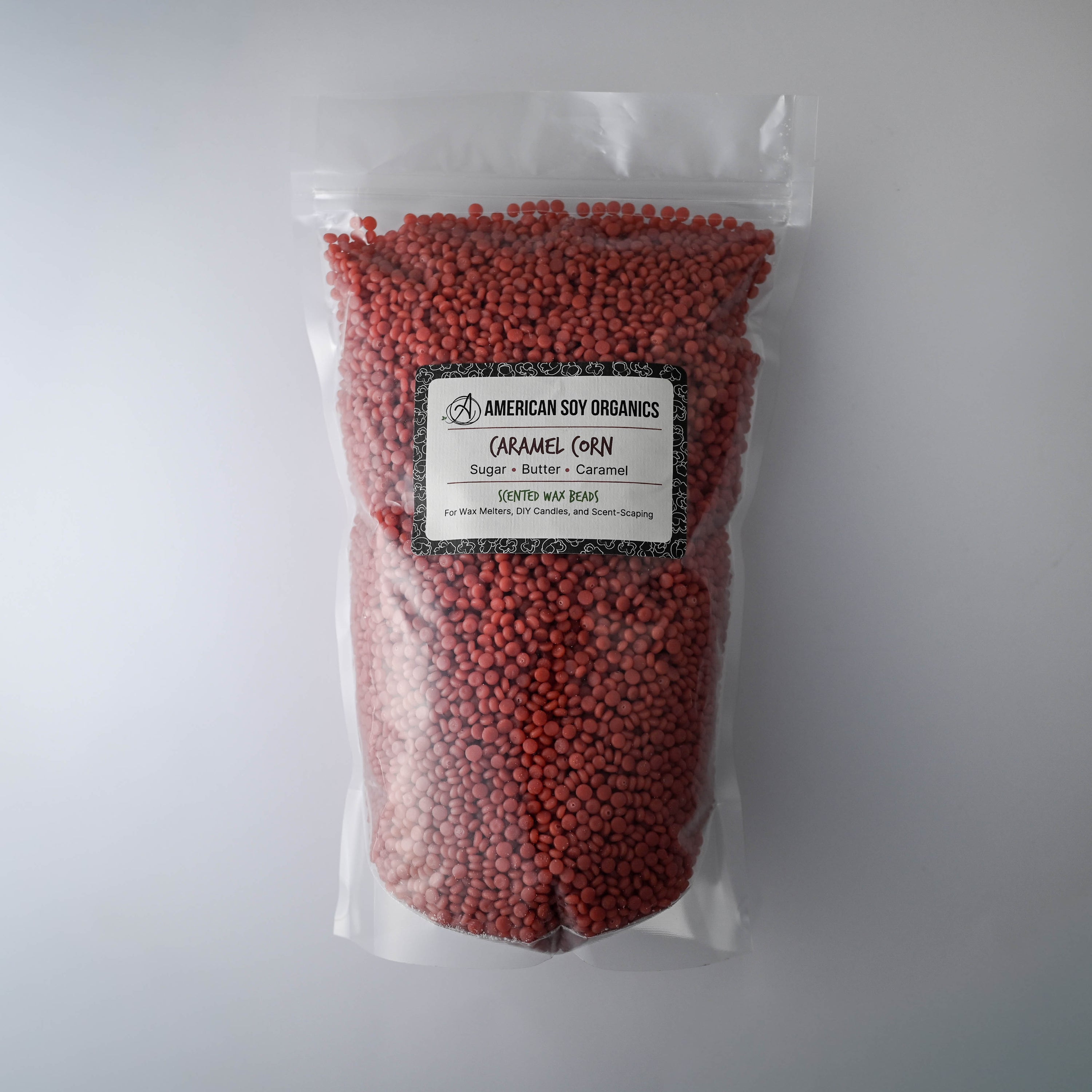 Bag of red caramel corn scented wax beads on a white background