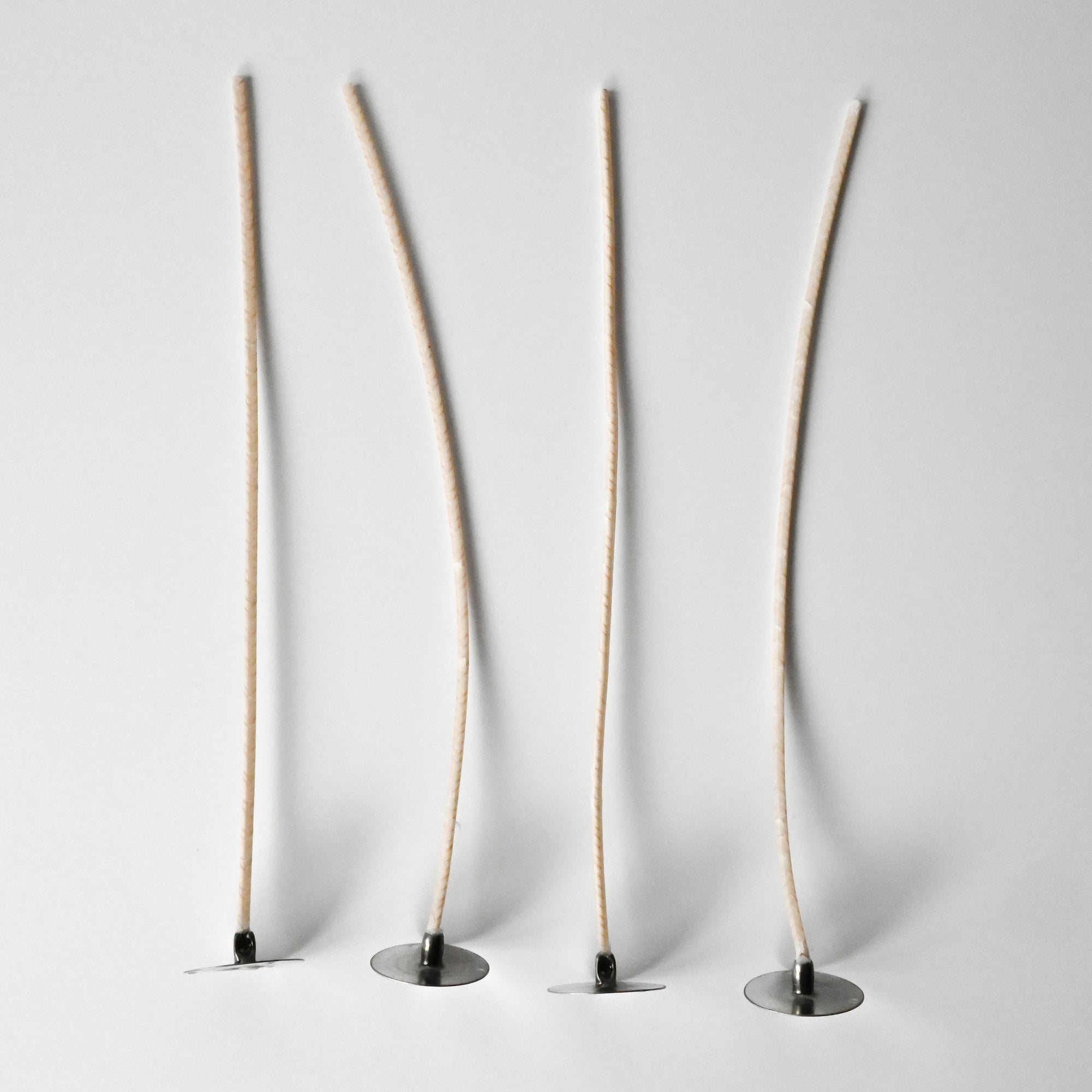 Tall beige wicks in a small round black base against a white background