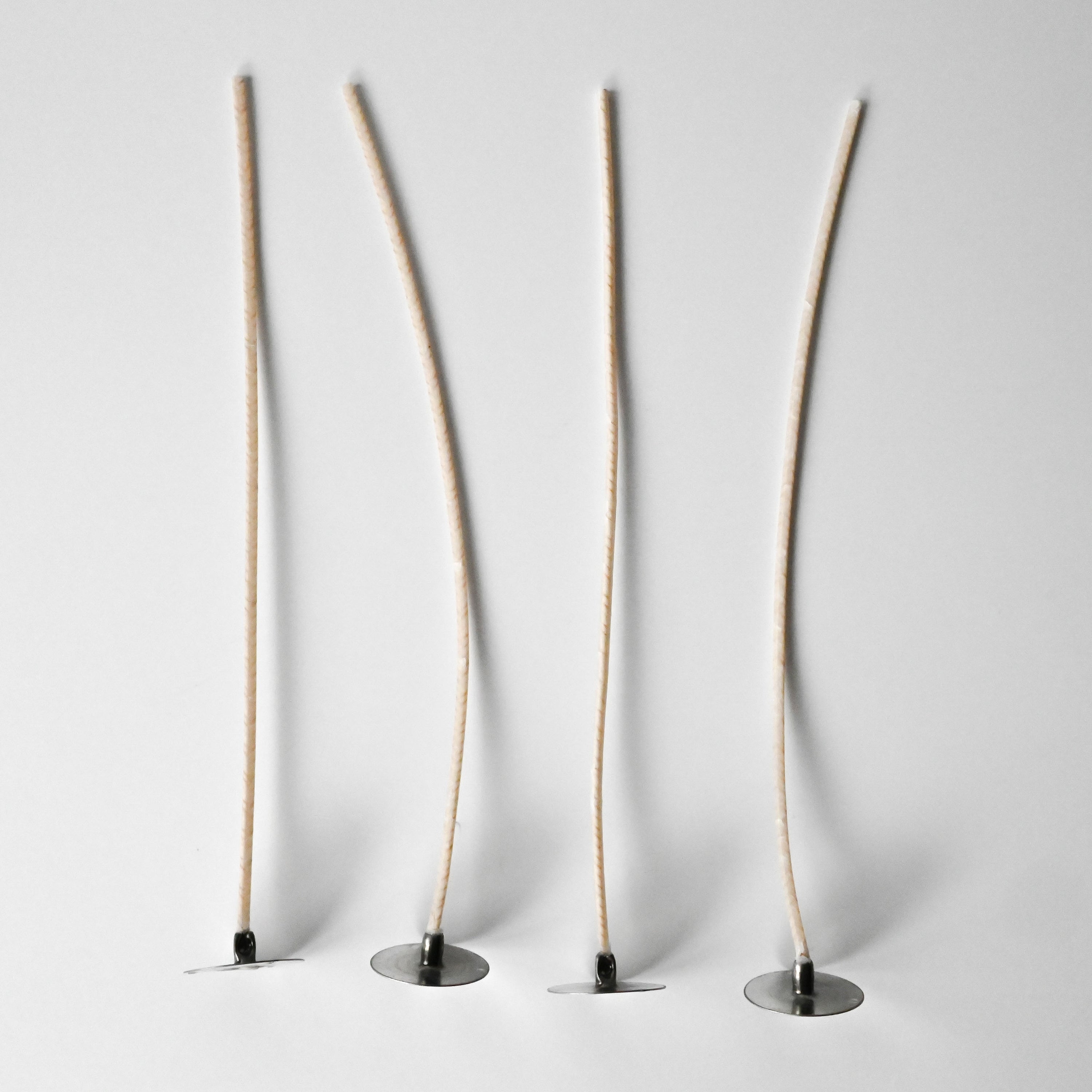 Tall beige wicks in a small round black base against a white background