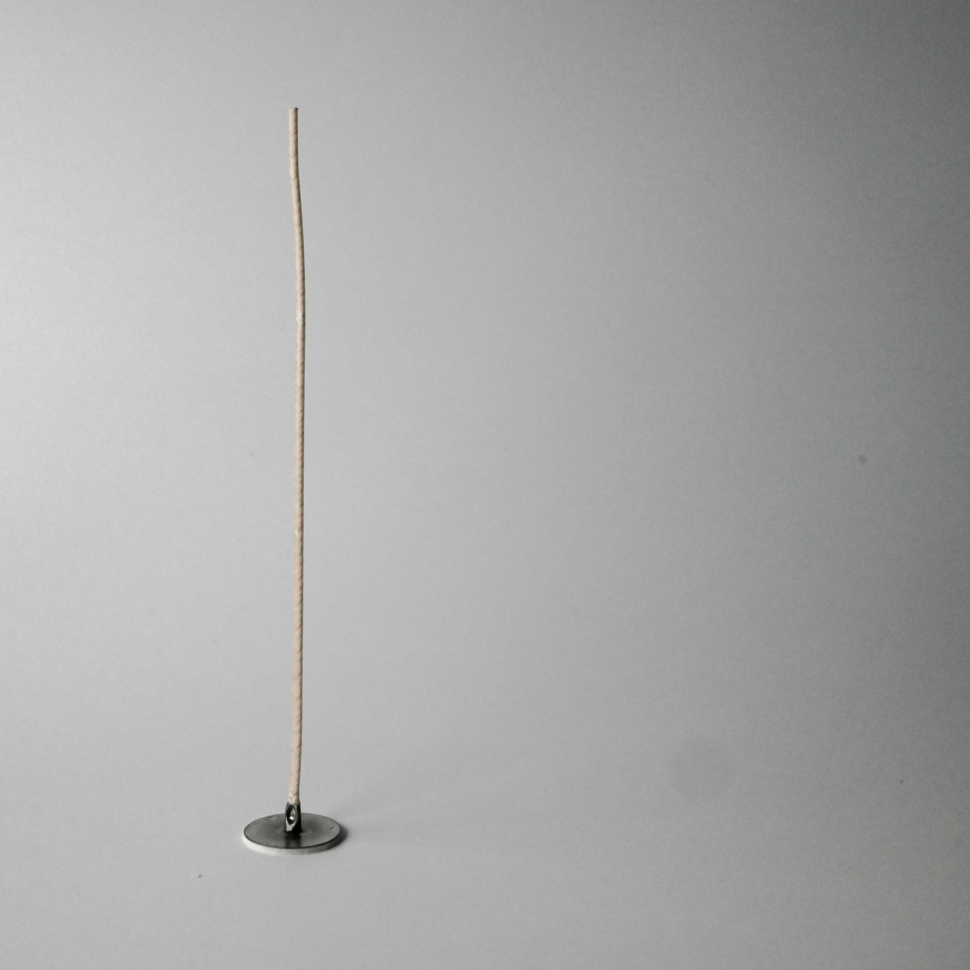 Standing candle wick on a light gray background