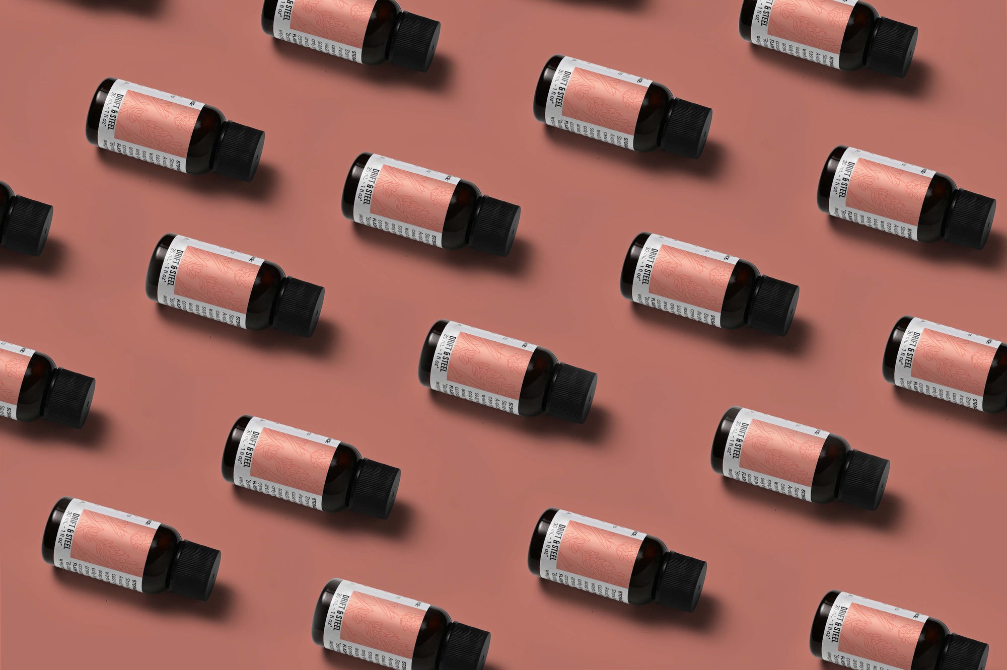 Pattern of Drift & Steel fragrance oil bottles on a rose colored background