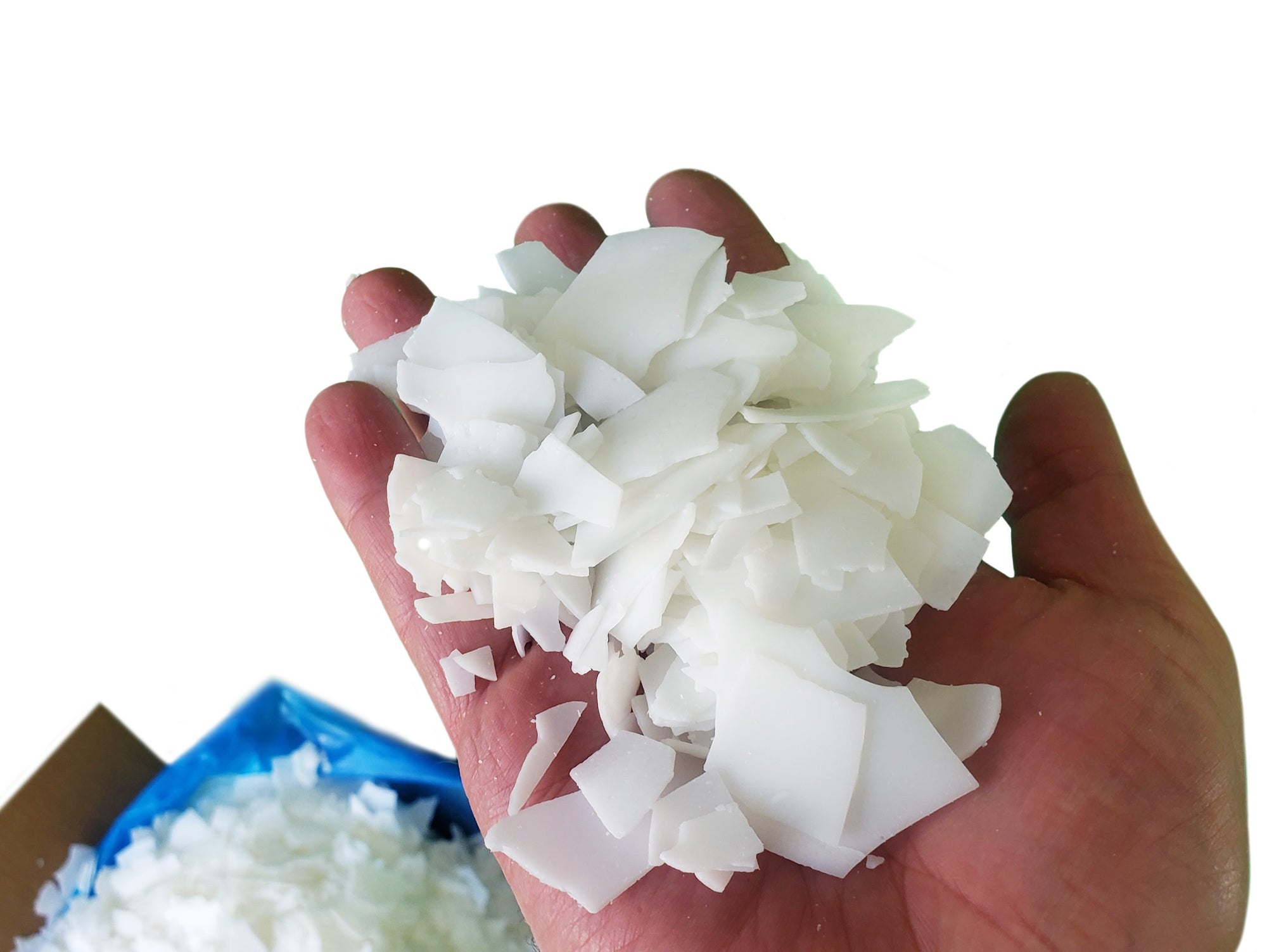 Hand holding a handful of white wax flakes against a white background