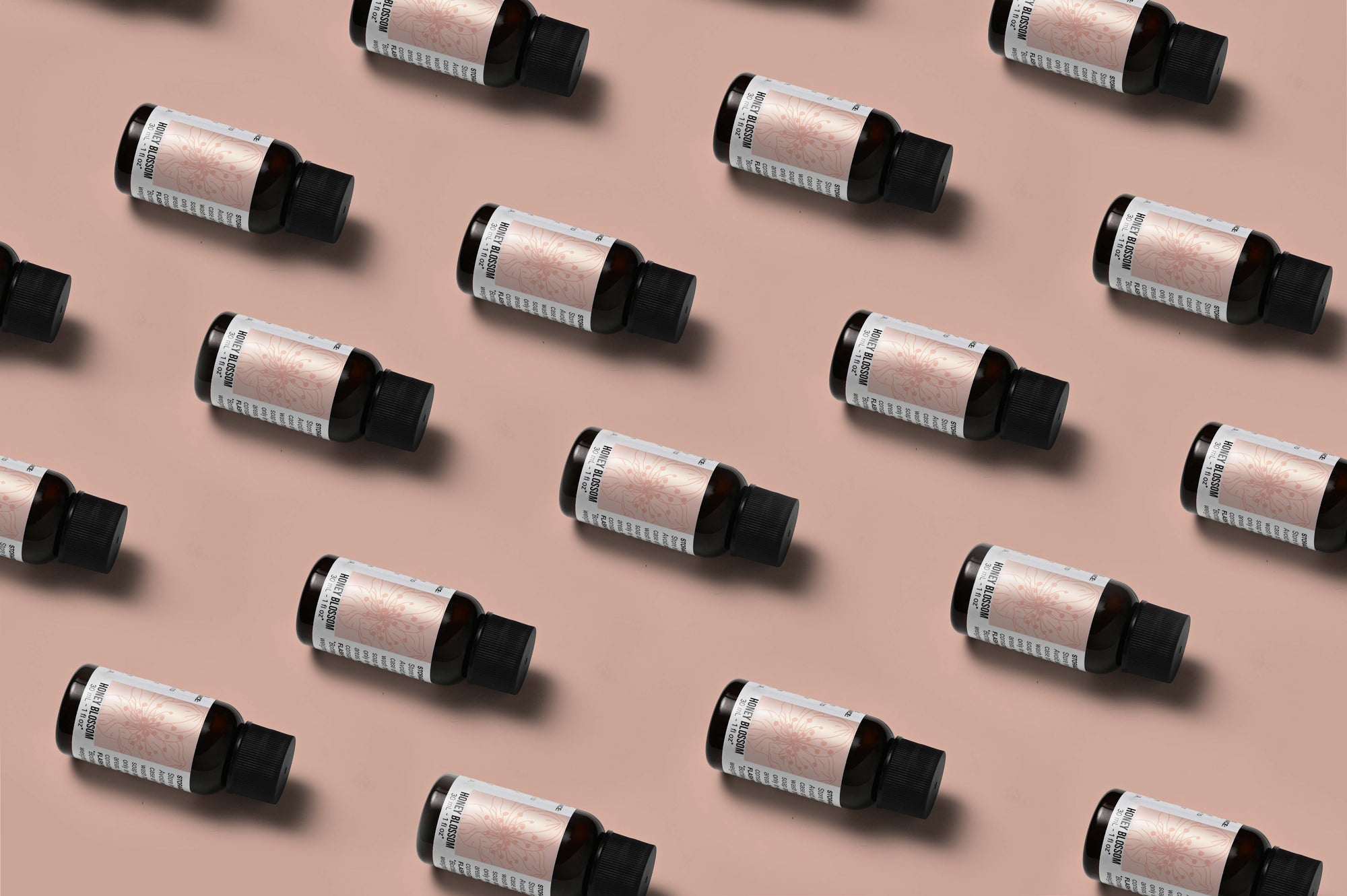 Pattern of Honey Blossom fragrance oil bottles on a rose colored background