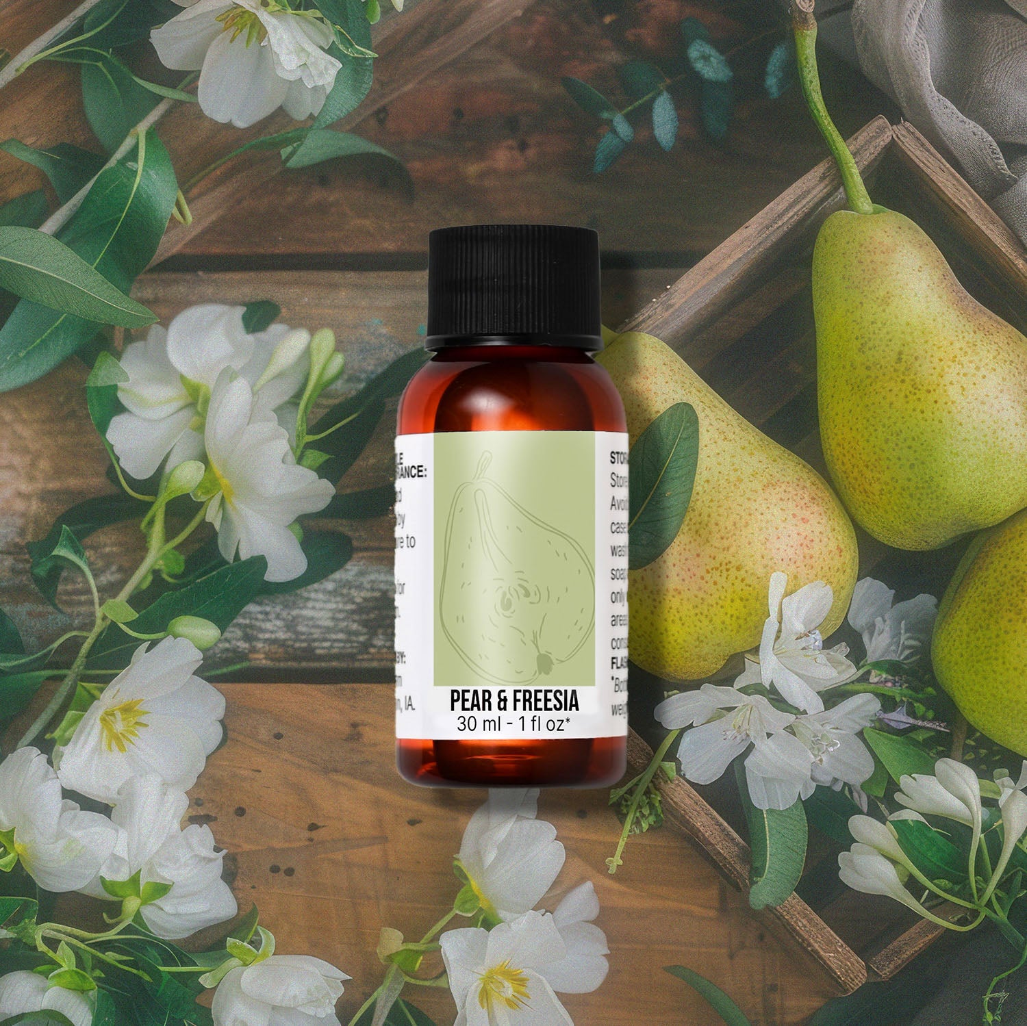 Bottle of 'Pear & Fresia' fragrance oil with pears and flowers on a wooden background