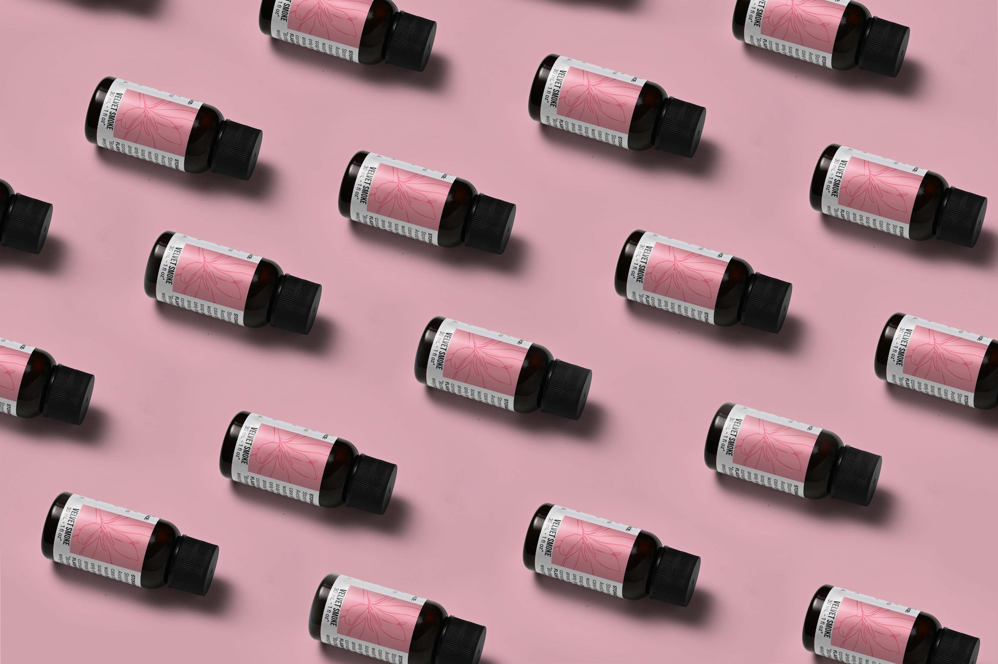 Pattern of Velvet Smoke fragrance oil bottles on a light pink background