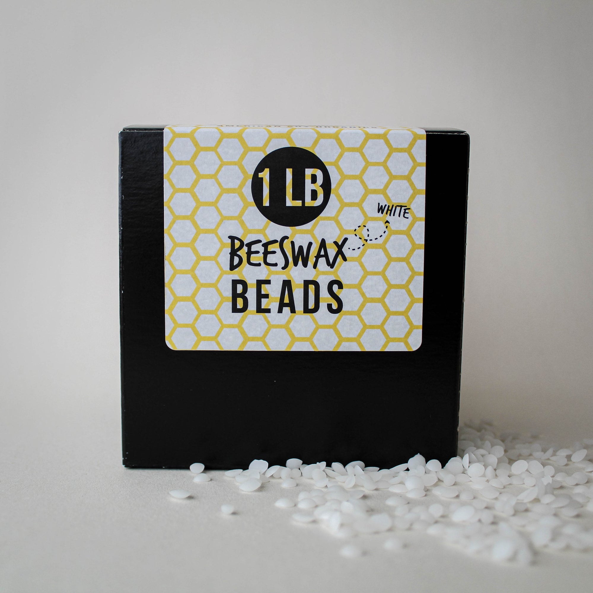 Box of white beeswax beads with a label indicating '1 LB White Beeswax Beads' on a white background.