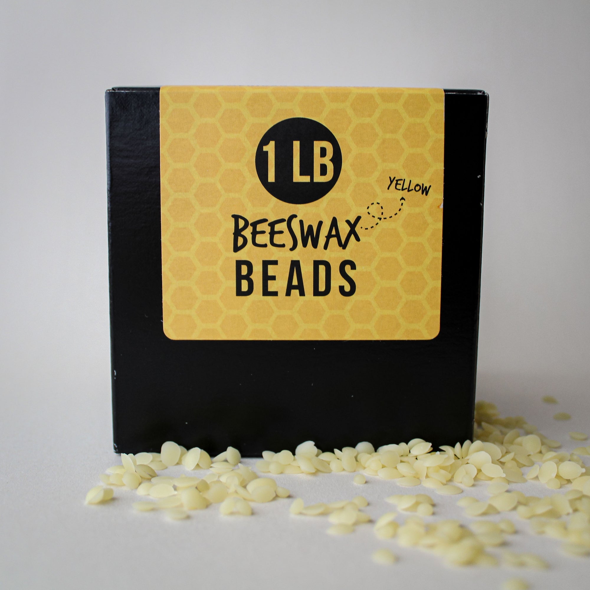 Box of yellow beeswax beads with a label indicating '1 LB Yellow Beeswax Beads' on a white background.