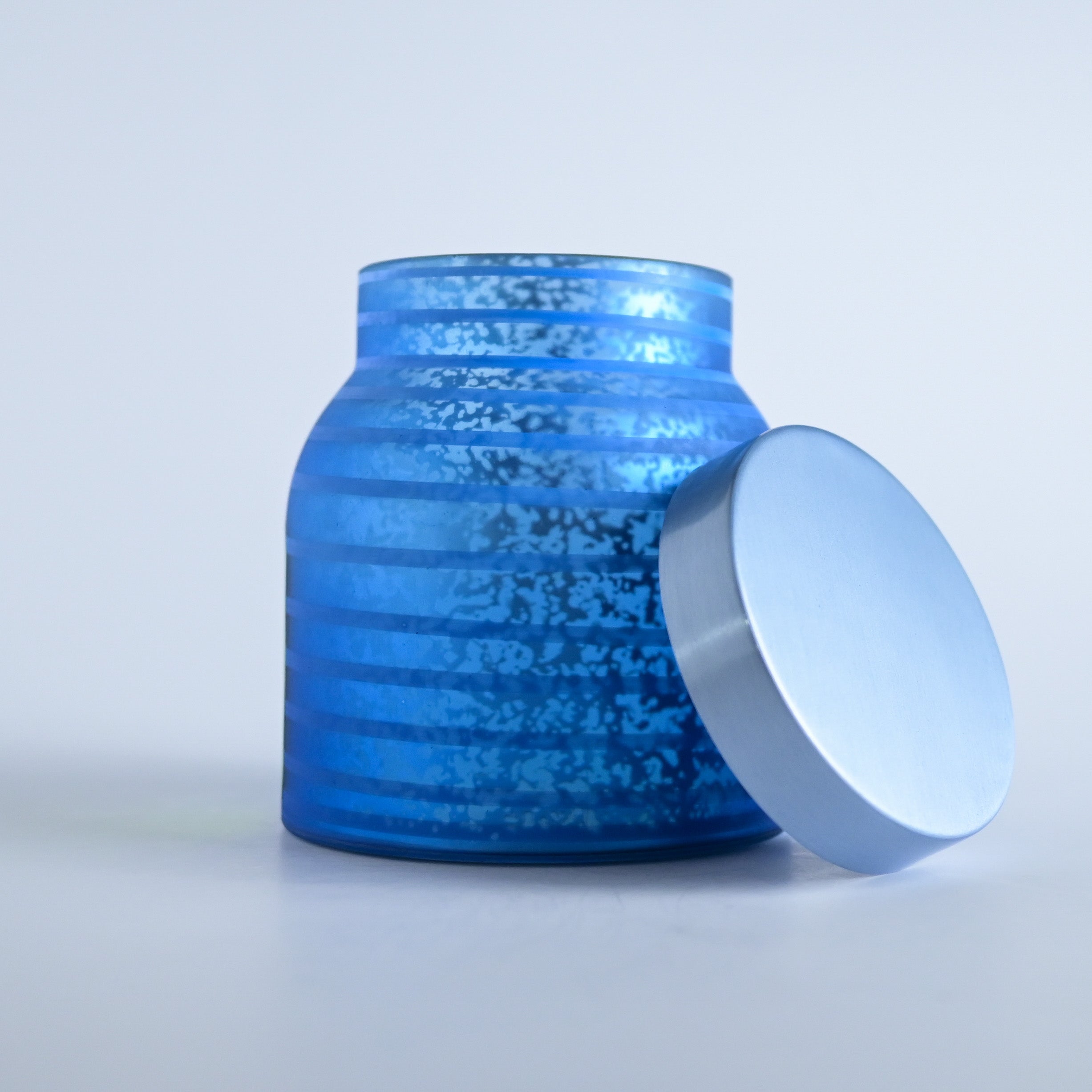 Blue striped jar with a silver lid on a white background