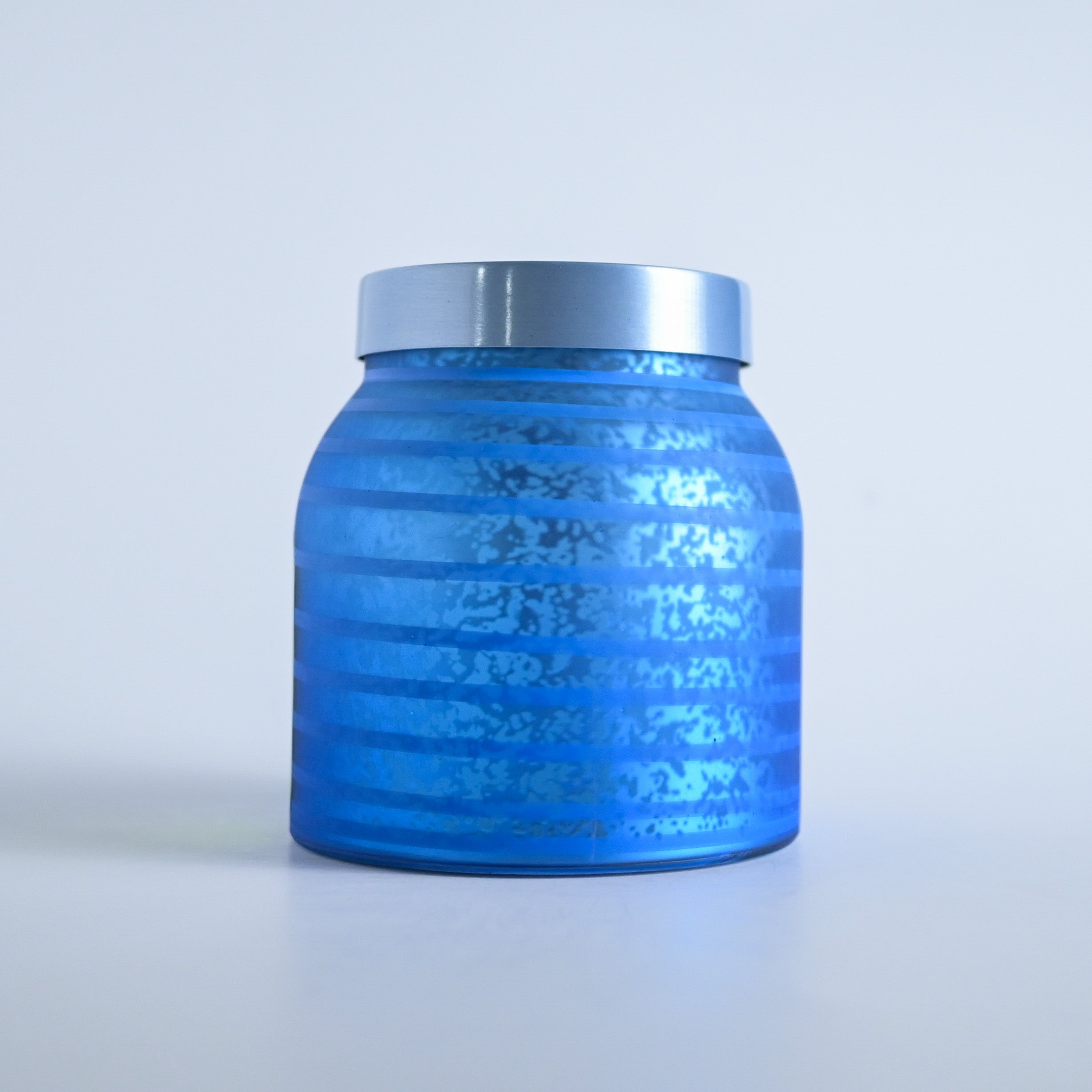 Blue striped  jar with a silver lid on a white background