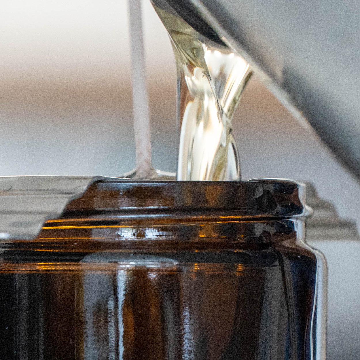 Wax liquid being poured into a black container with a blurred background