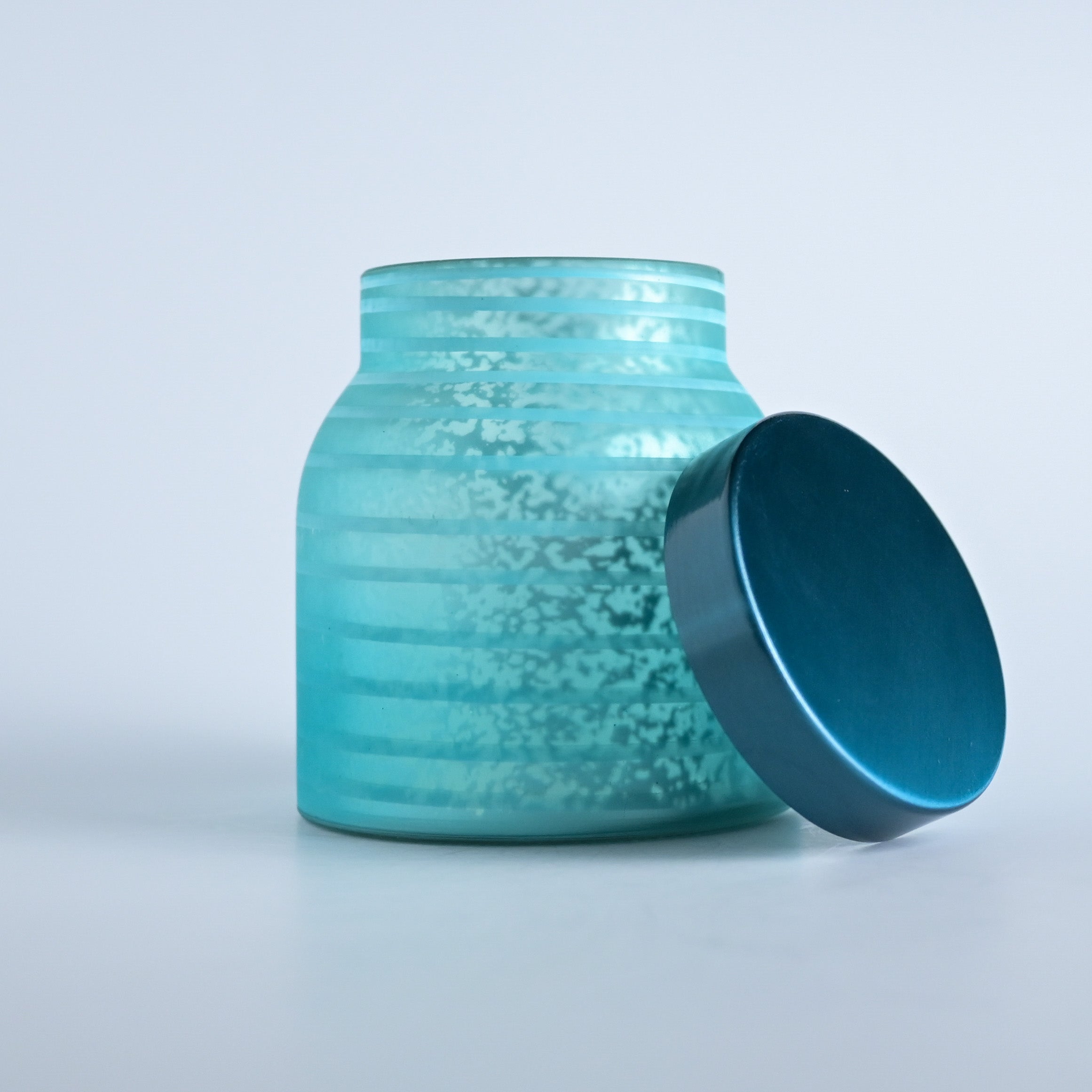 Teal striped jar with a teal lid on a white background