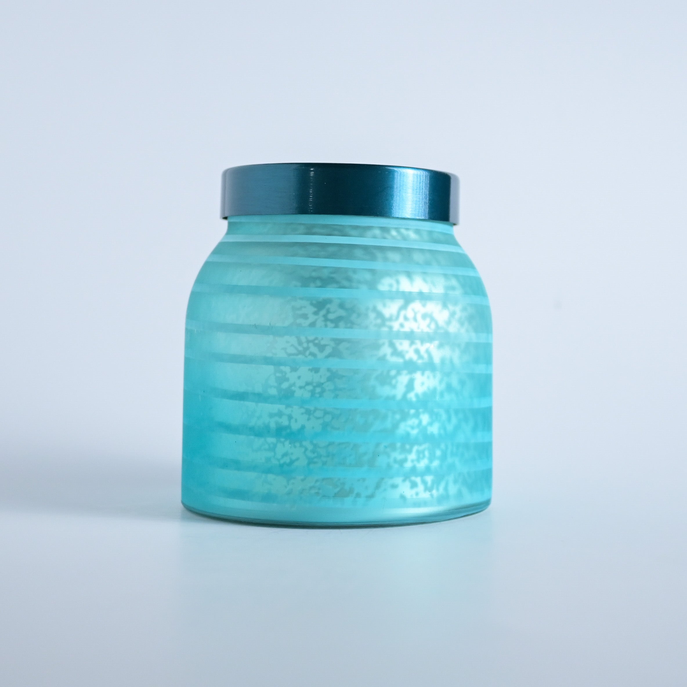 Teal striped jar with a teal lid on a white background