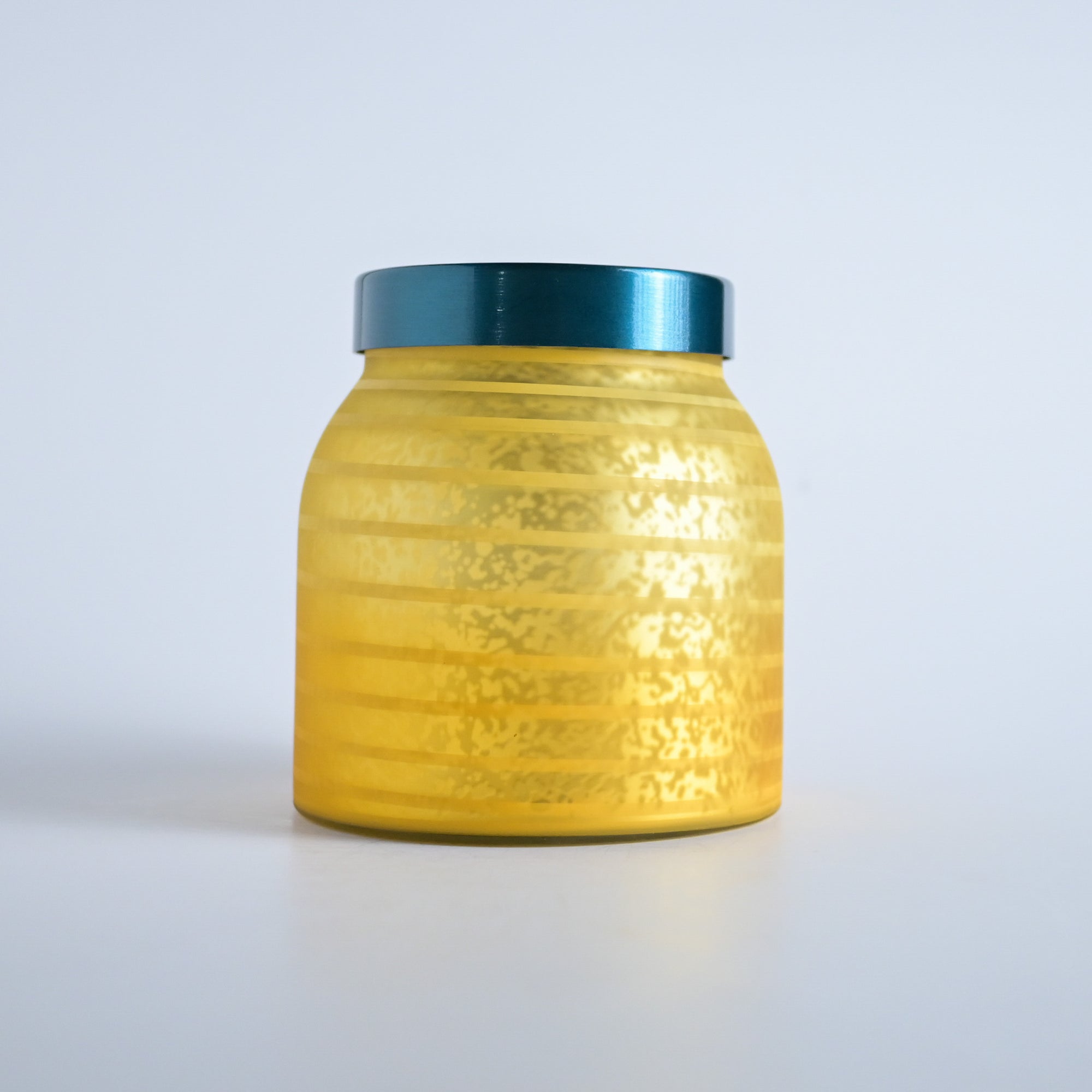 Golden yellow striped jar with a teal lid on a white background