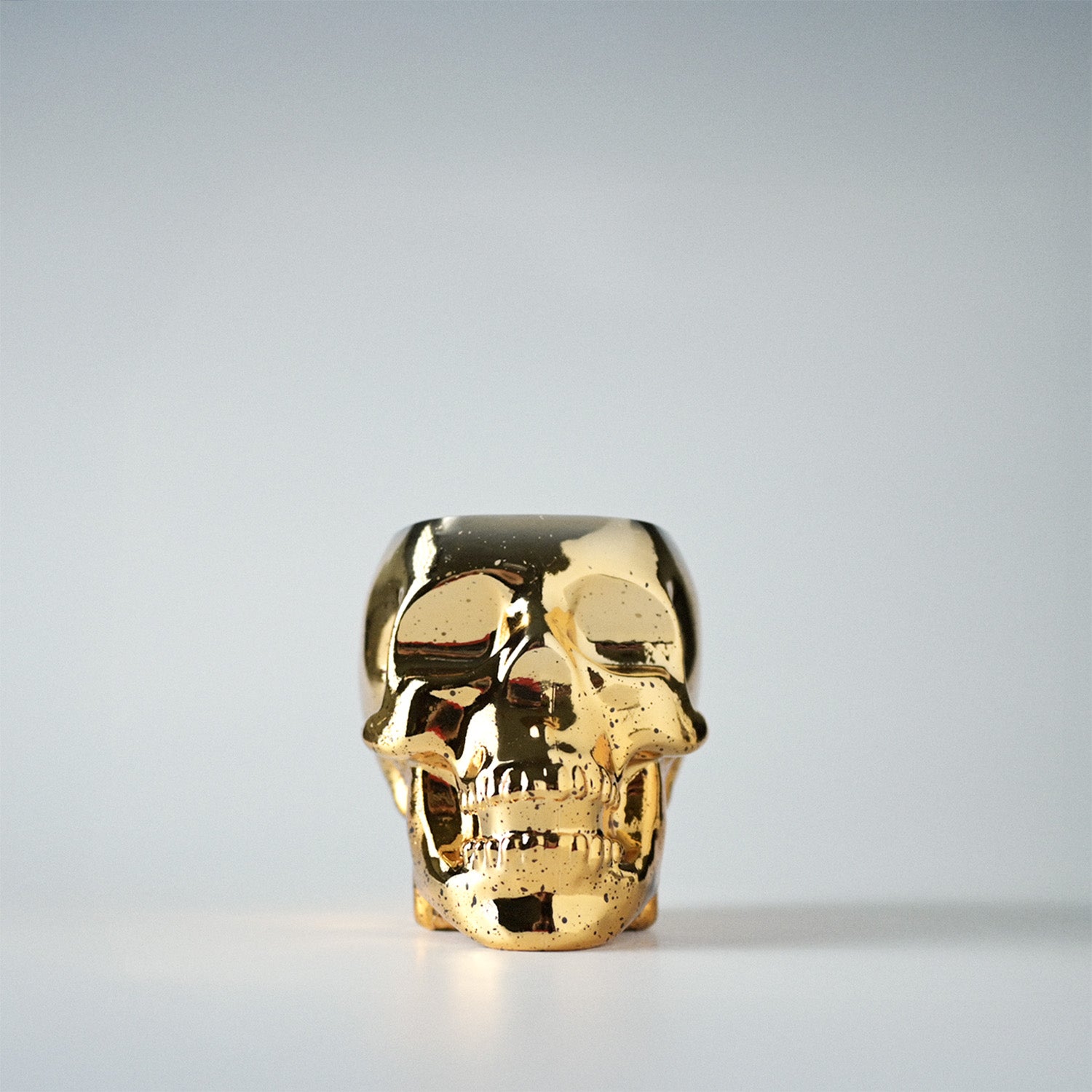 Gold skull-shaped jar on a white background