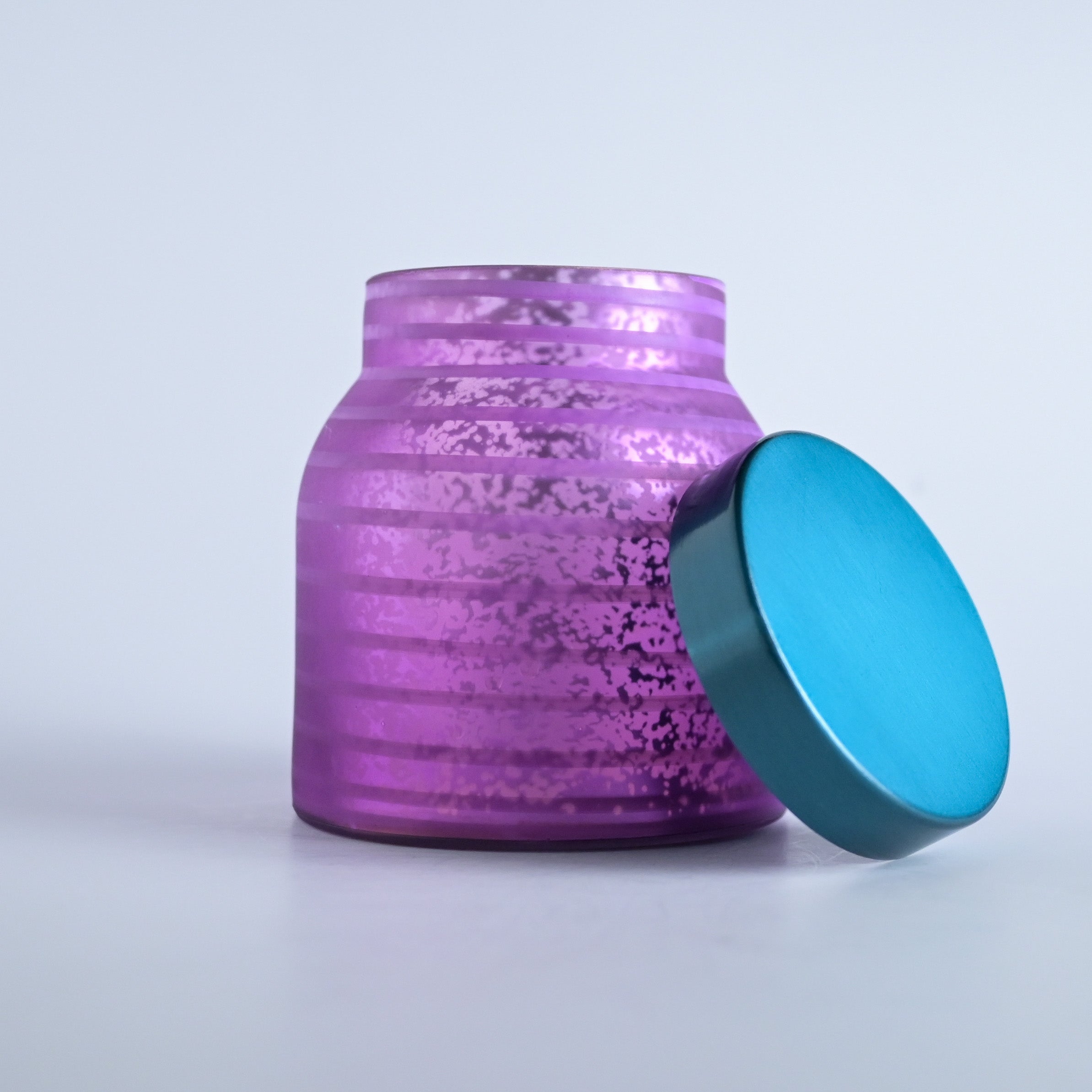 Purple striped jar with a teal lid on a white background
