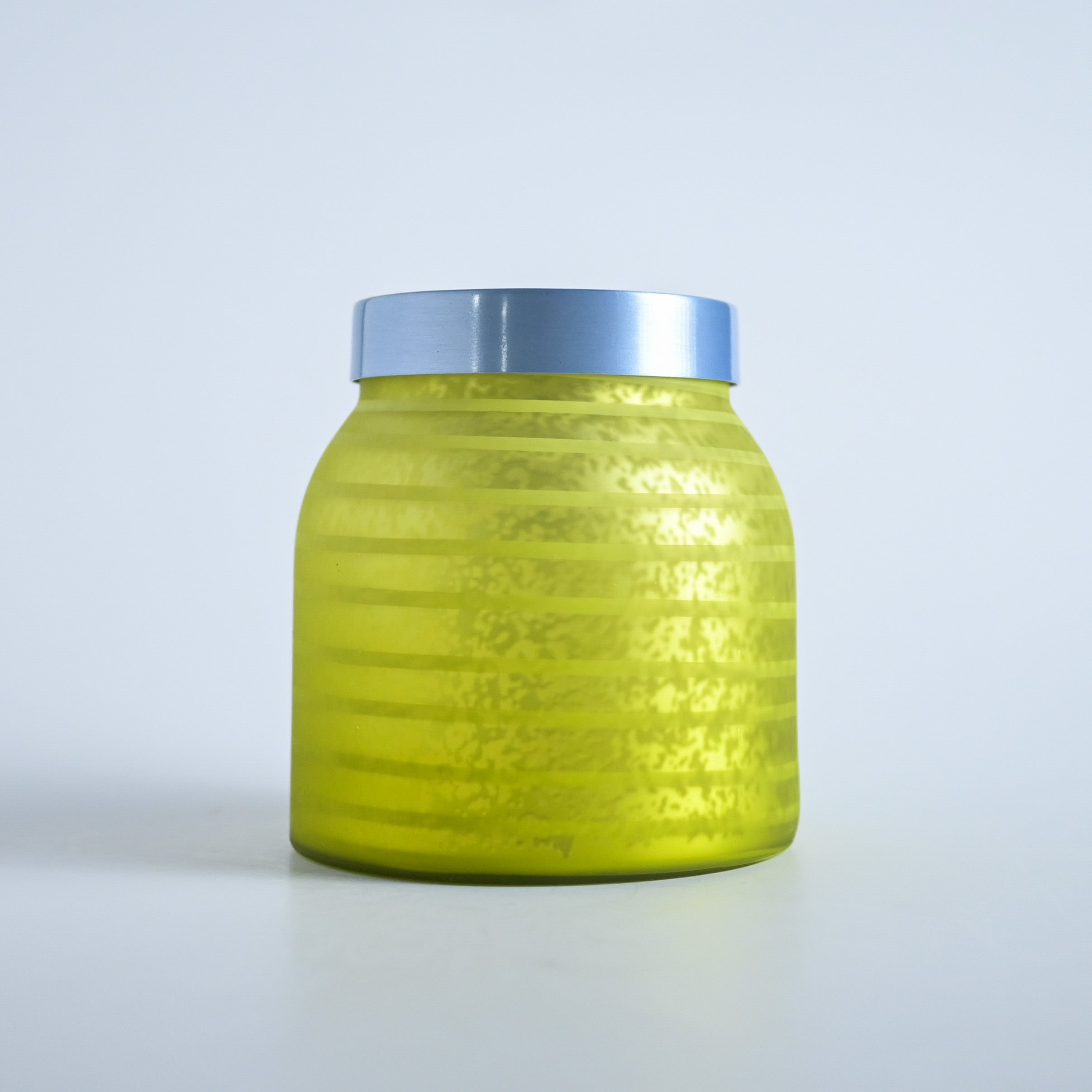 Yellow striped jar with a silver lid on a white background