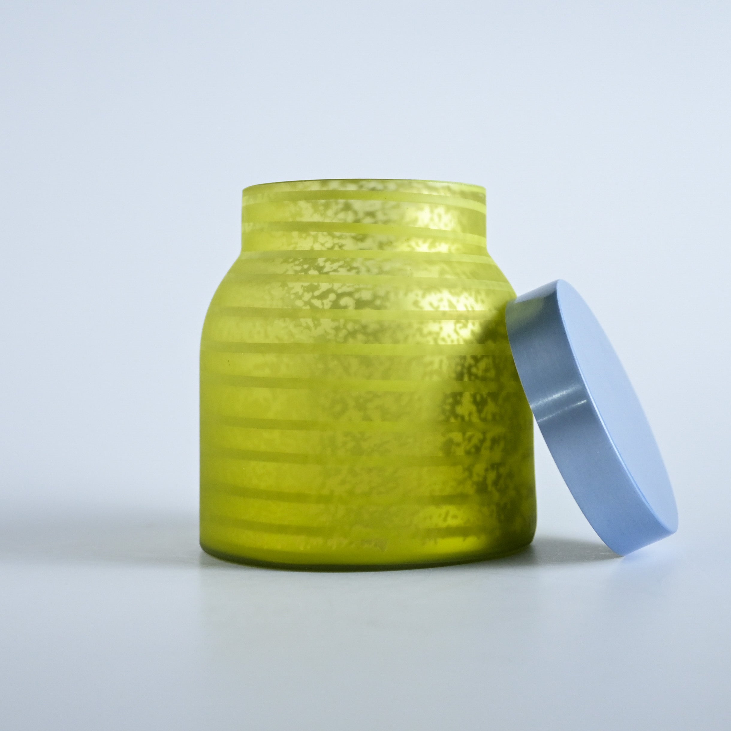 Yellow striped jar with a silver lid on a white background