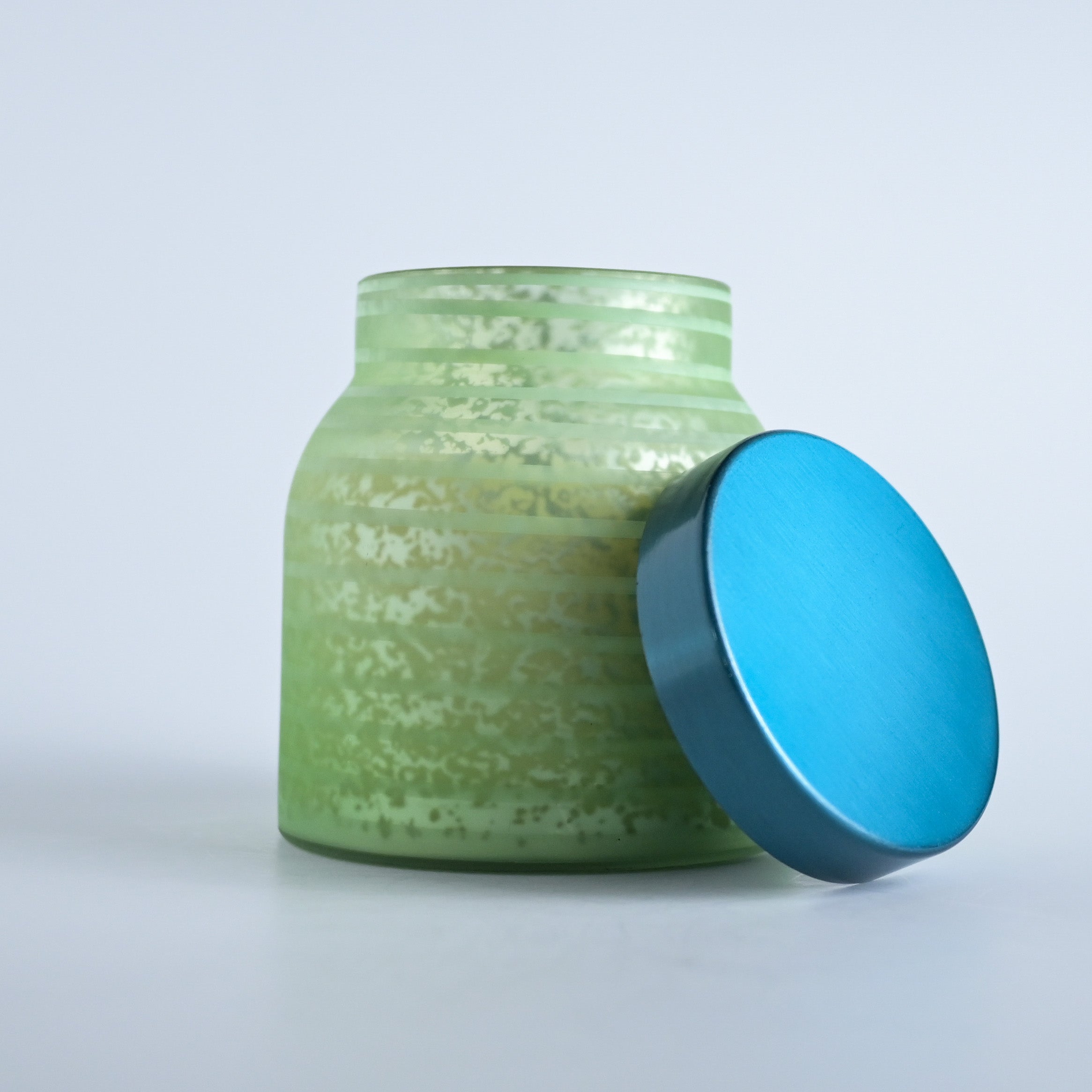 Green striped jar with a teal lid on a white background