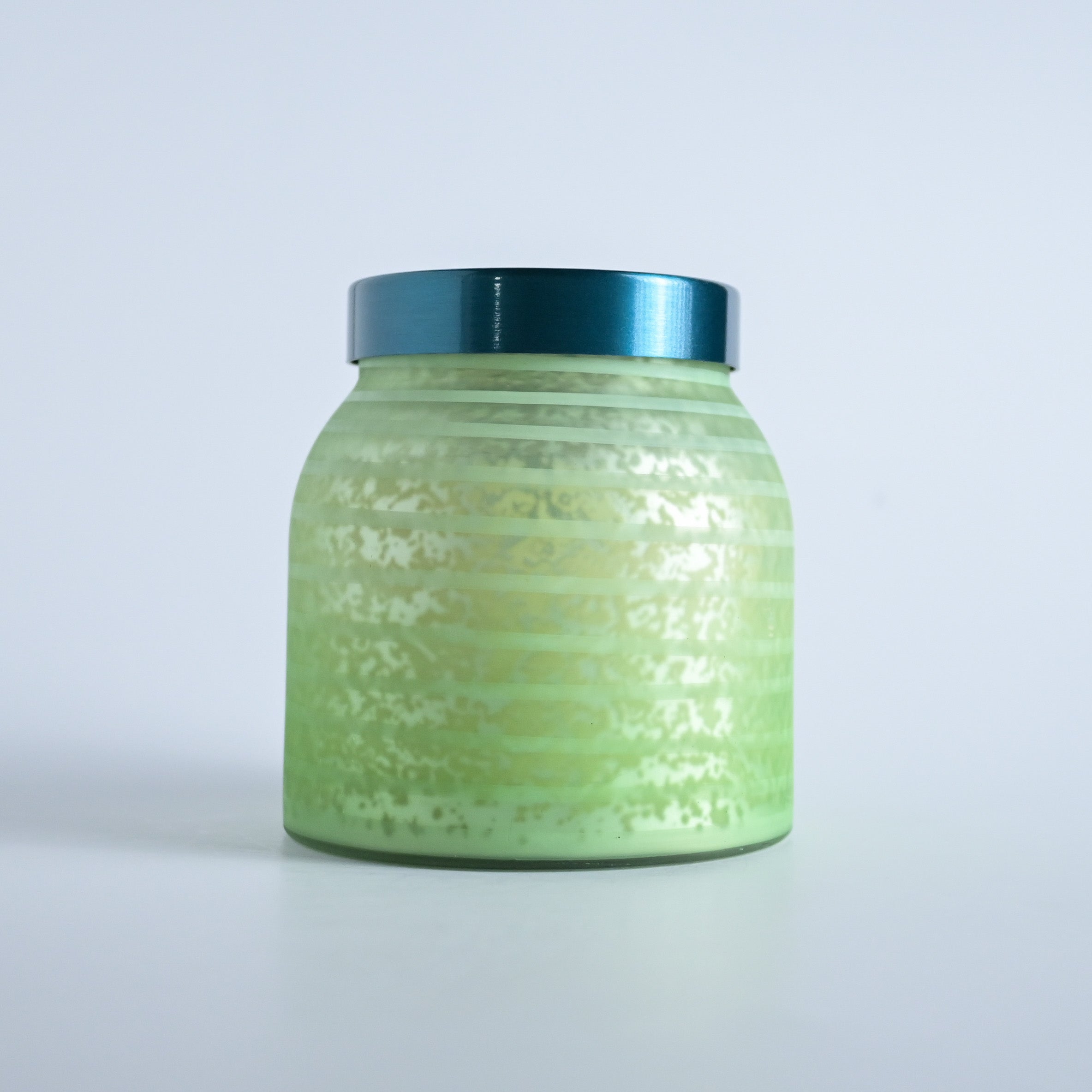 Green striped jar with a teal lid on a white background