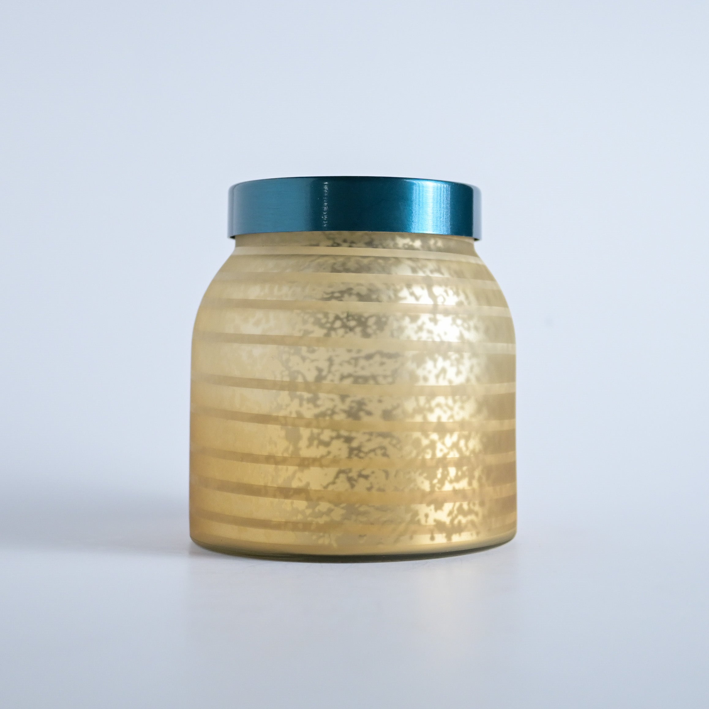 Gold striped jar with a teal lid on a white background