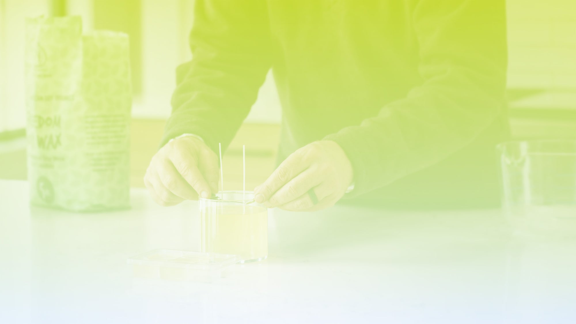 Person's hands working with a candle on a light background