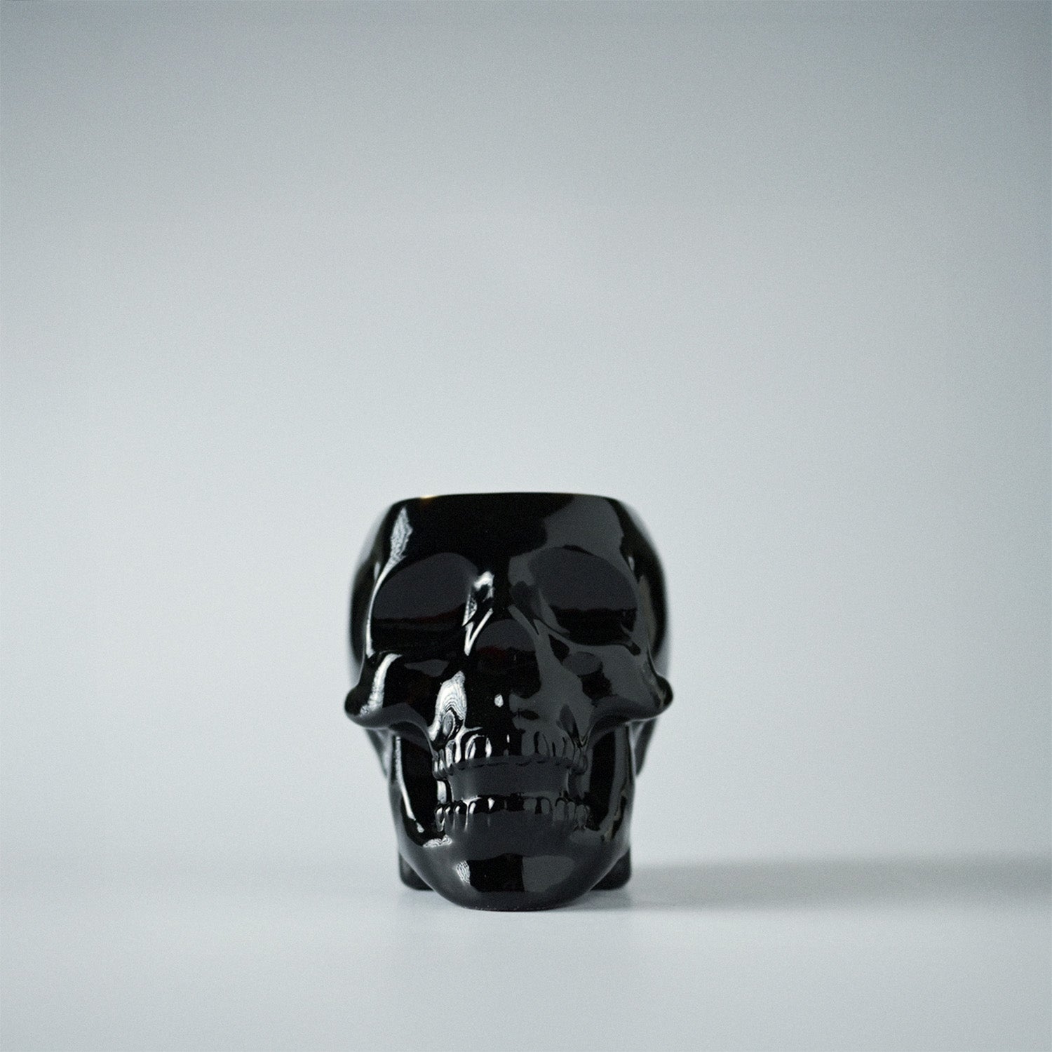 Black skull-shaped jar on a white background