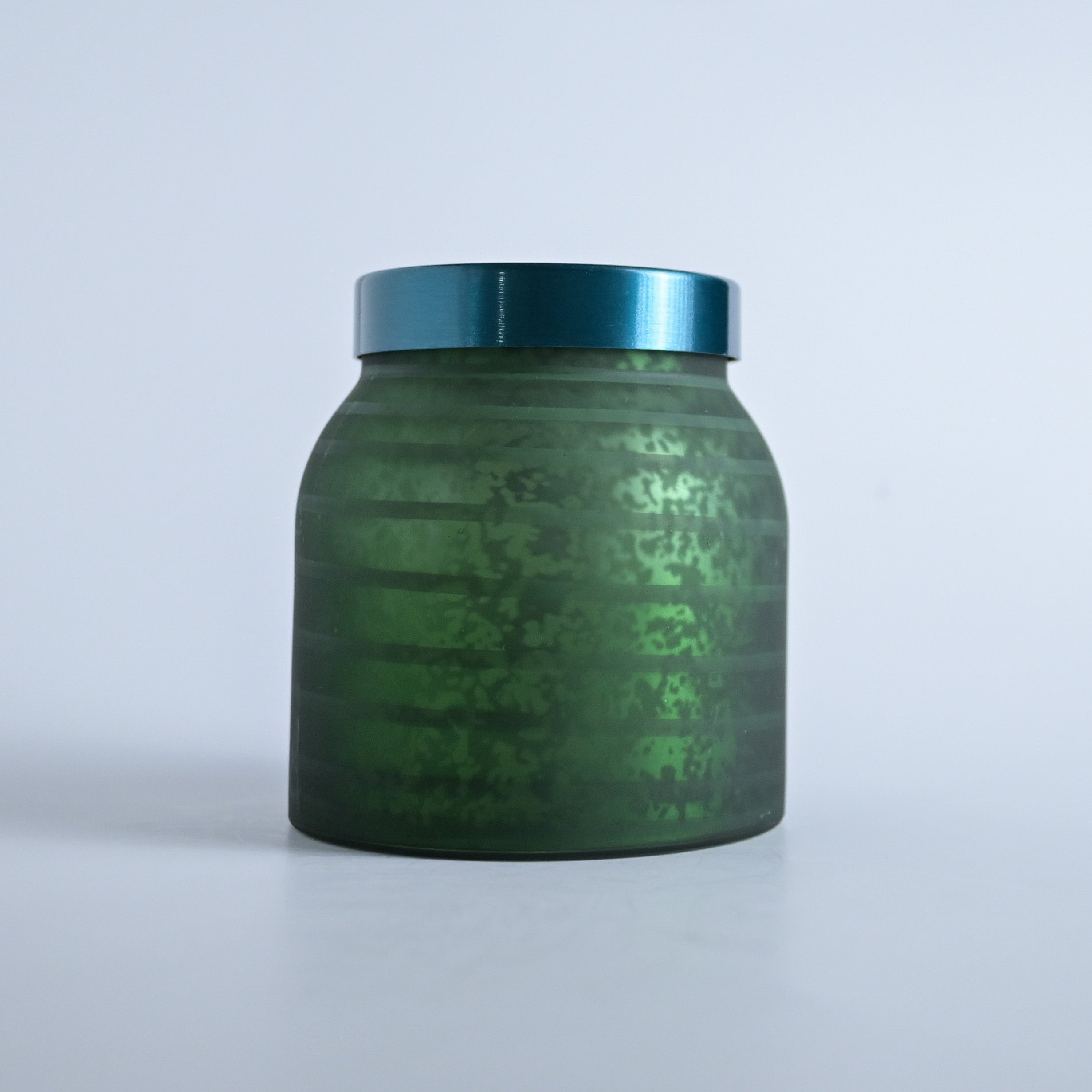Dark green striped jar with a teal lid on a white background