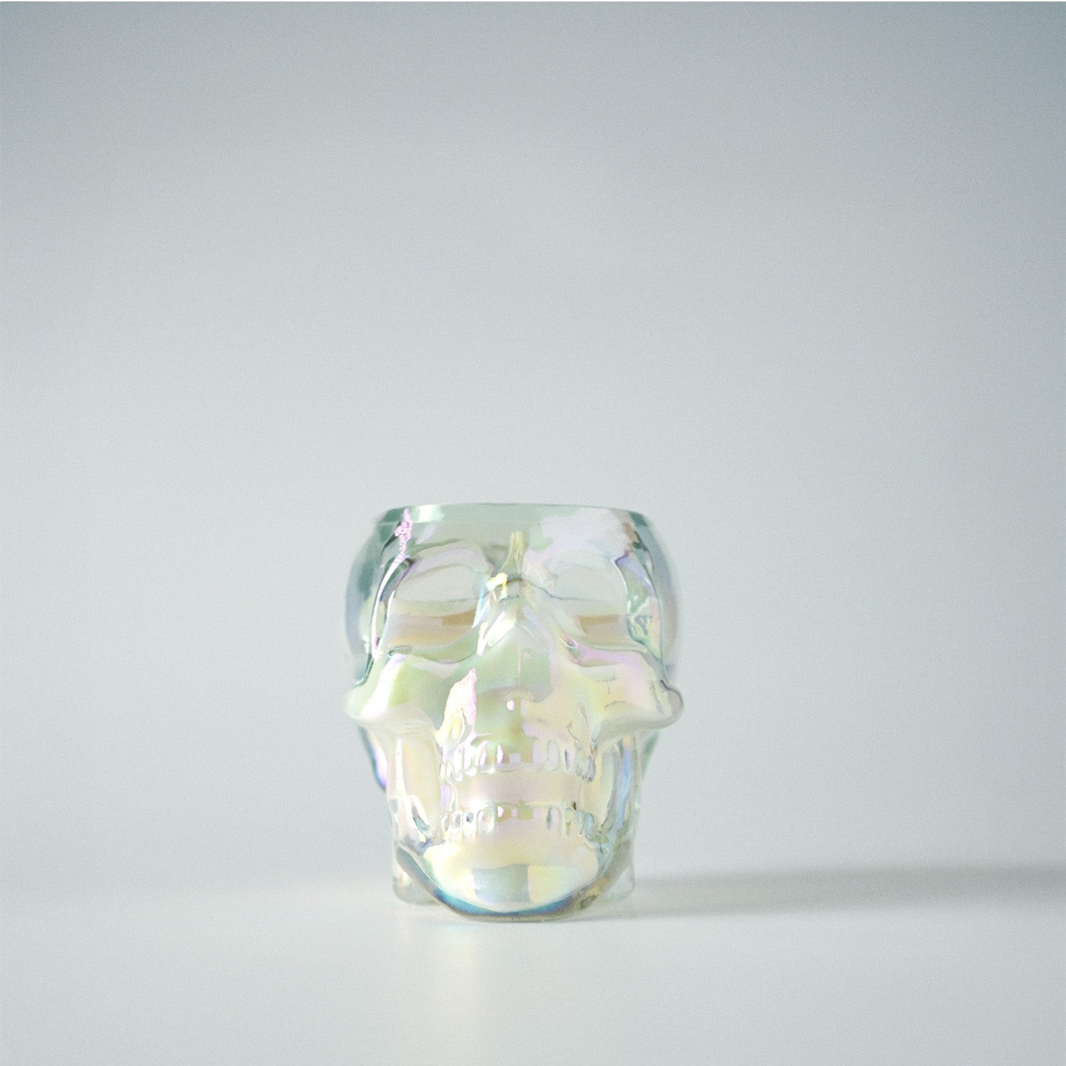 Glass skull jar with iridescent finish on a white background