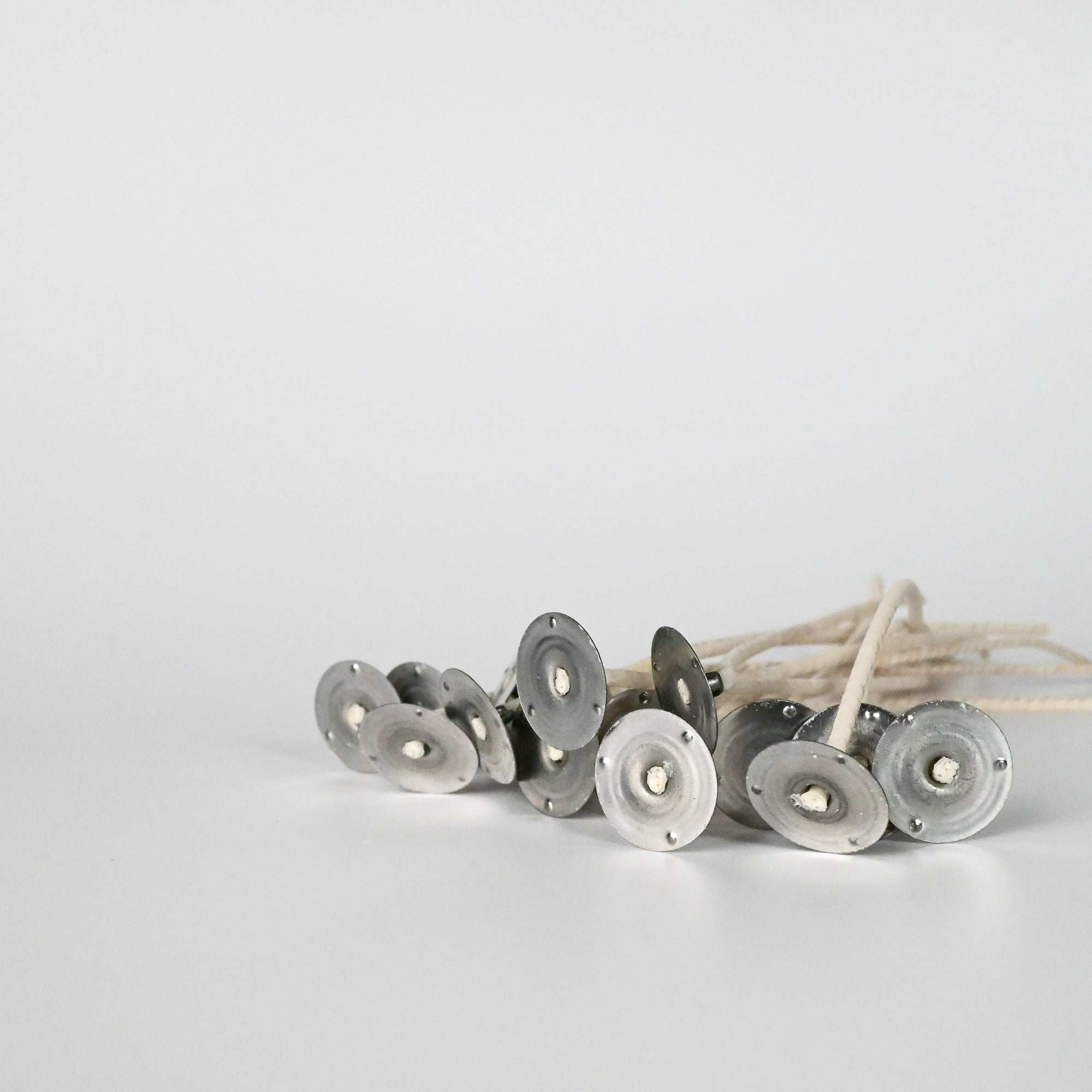 Multiple wicks positioned flat, with the bottom of the metal bases facing upward on a white background