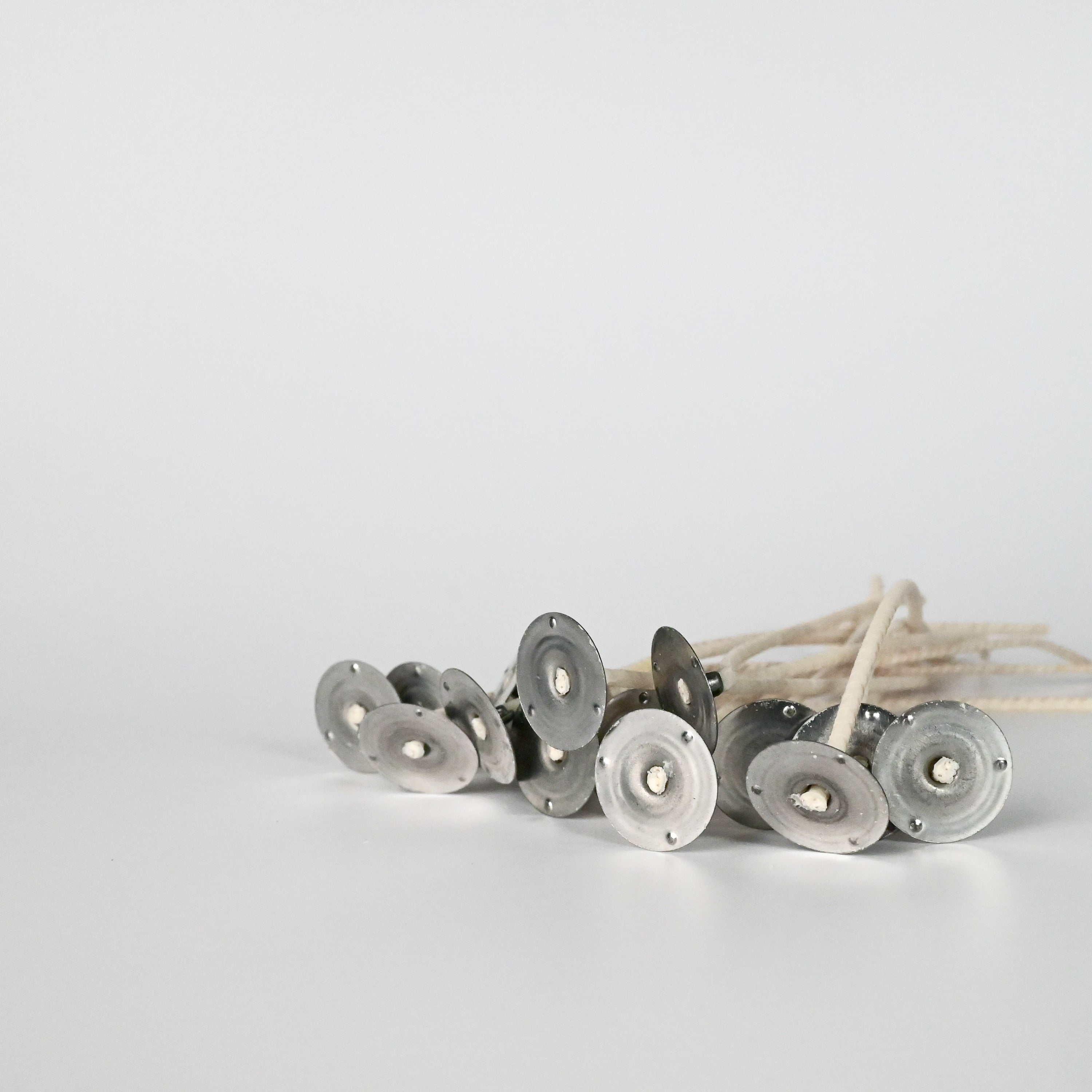 Multiple wicks positioned flat, with the bottom of the metal bases facing upward on a white background